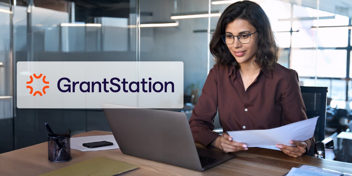 Person using a laptop, reviewing a document. The GrantStation logo is inset.