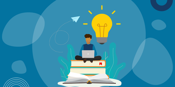 A man sitting on a stack of books taking a webinar on a laptop