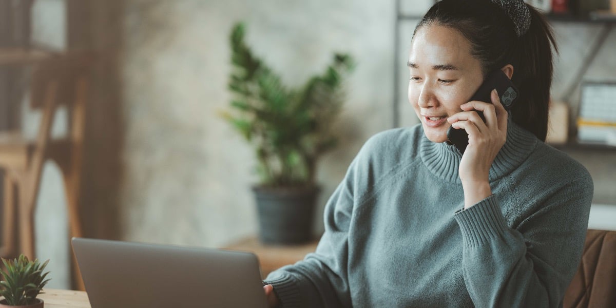 Person at their computer, talking on the phone.