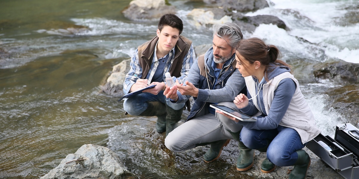 Field researchers studying water quality alongside a river.