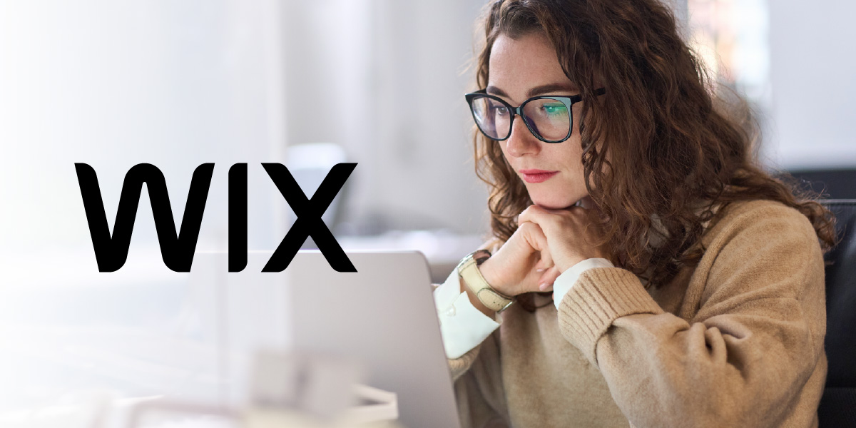 Office worker looking intently at their laptop. The Wix logo is inset.